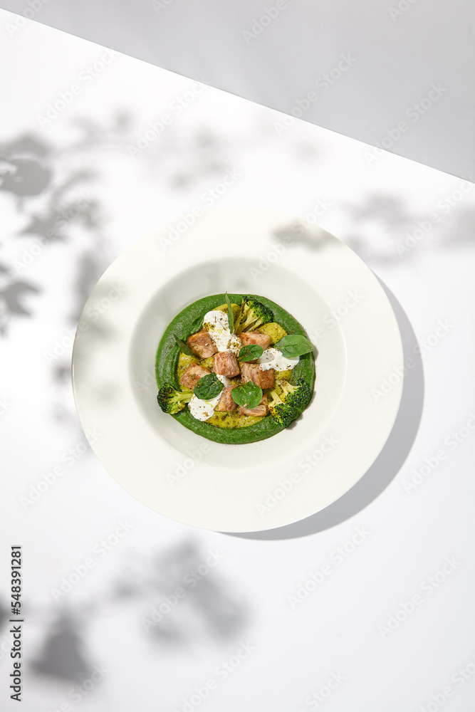 Creative dish from roasted chicken and broccoli puree on white plate. Sliced baked chicken with vegetables and creamy espuma in summer menu. Creative dish from roasted chicken and broccoli puree on white plate. Sliced baked chicken with vegetables and creamy espuma in summer menu.