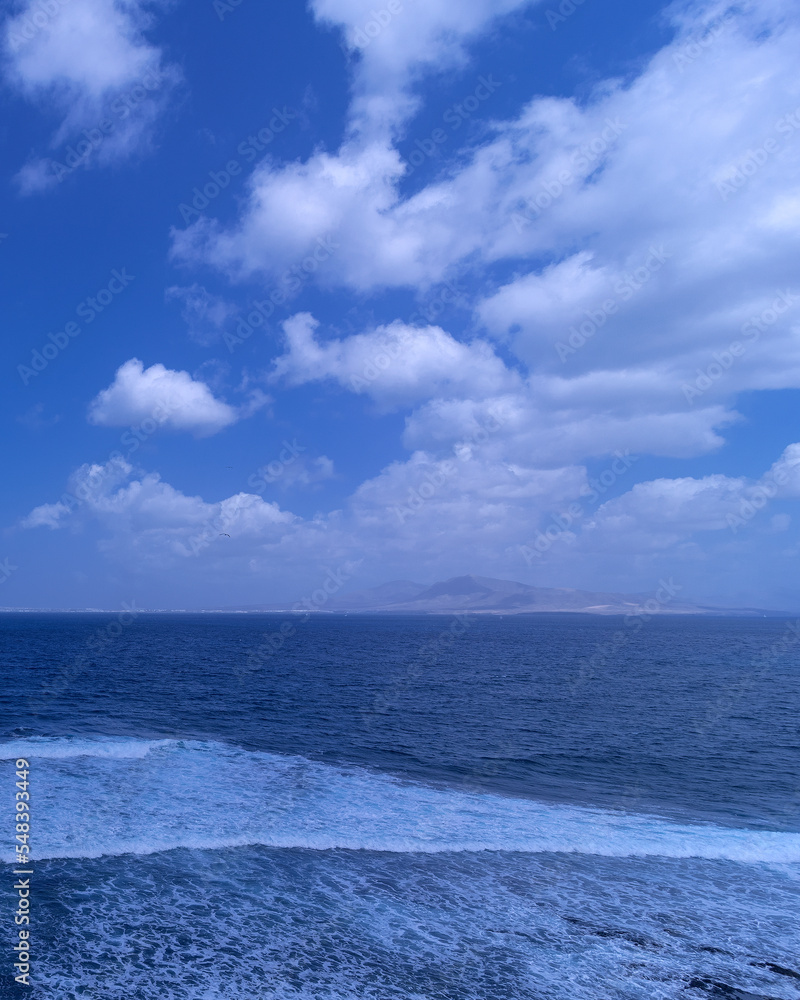 Atlantic ocean with strong waves and view of Lanzarote island in distance, Canary Islands, Spain