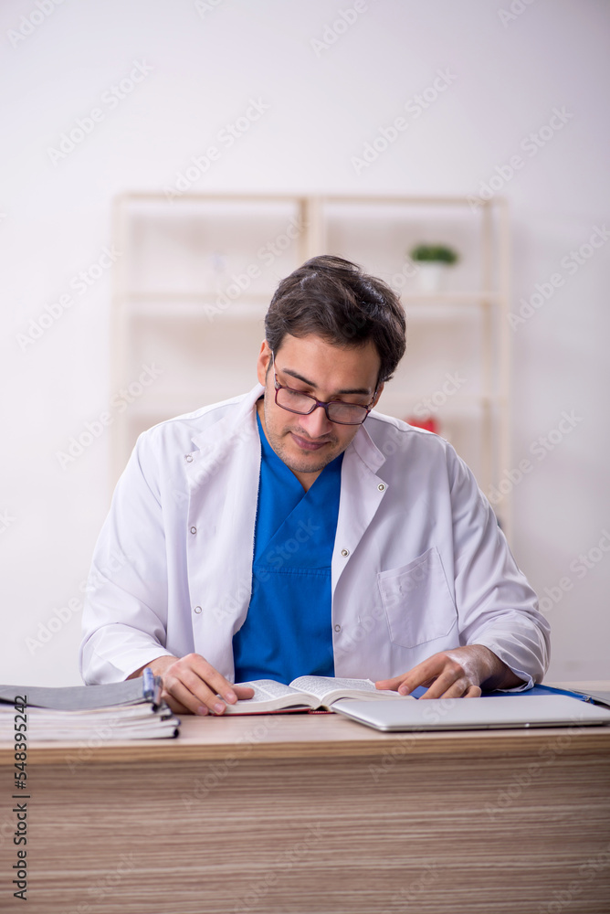 Young male doctor student reading book in the clinic Young male doctor student reading book in the clinic