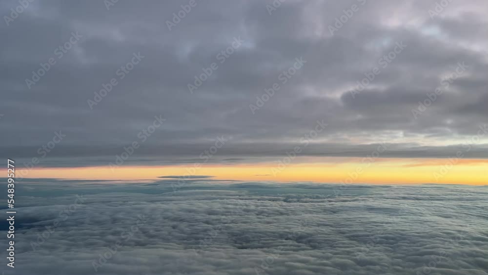Pilot view from a jet cockpit while flying between layers of clouds at dawn with an orange sky, at 10000m high in a cold winter moorning. Pilot view from a jet cockpit while flying between layers of clouds at dawn with an orange sky, at 10000m high in a cold winter moorning.