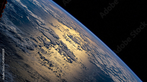 Aerial view of earth and clouds in the atmosphere over the Atlantic ocean with sunlight glinting over the sea. The elements of this image furnished by NASA. photo
