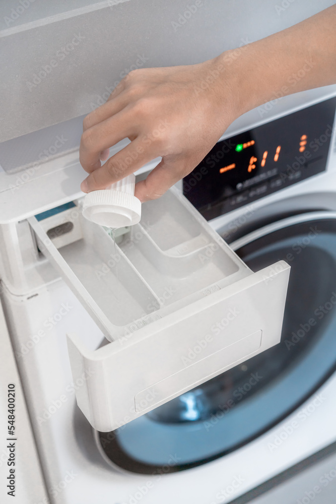 close up of hand pouring laundry detergent into the washing liquid sink. close up of hand pouring laundry detergent into the washing liquid sink.