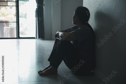 Schizophrenia with lonely and sad in mental health depression concept. Depressed woman sitting against wall at home with a shadow on wall feeling miserable. Women are depressed, fearful and unhappy.