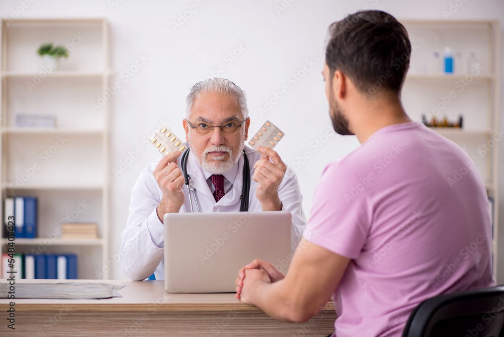 Obraz premium Young male patient visiting old male doctor