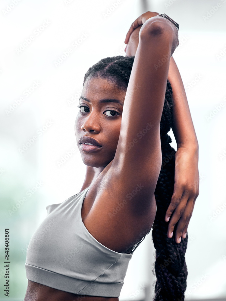Fototapeta premium Workout, portrait and black woman stretching arm for self care, wellness and health at club. Exercise, training and athlete warm up in gym for body cardio with serious and determined face.