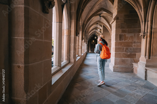 A girl traveler and tourist walks in the hall of an ancient monastery or the courtyard of the cathedral