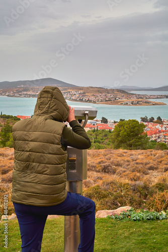 A man on an observation deck looks through a telescope.