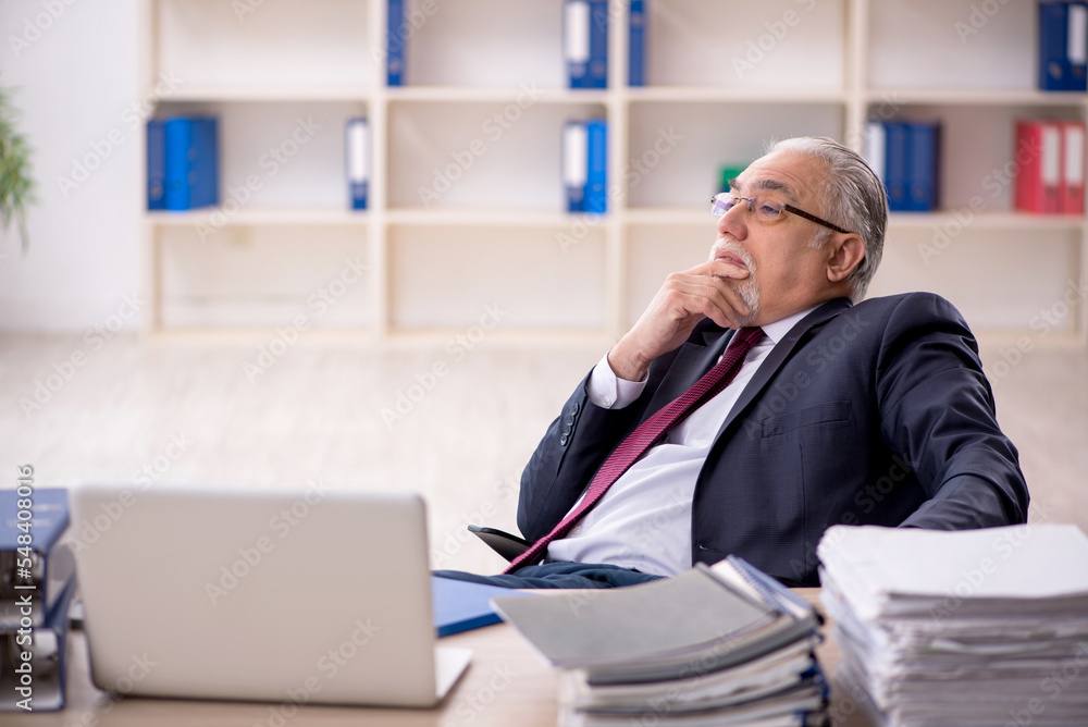 Old male employee sitting at workplace Old male employee sitting at workplace