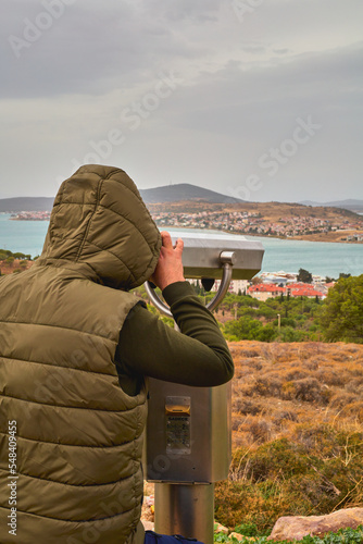  A man on an observation deck looks through a telescope.