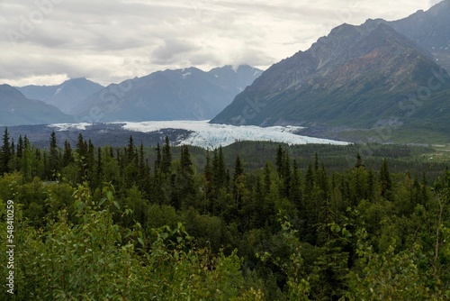 Scenic view of Matanuska Glacier against green Chugach Mountains in Alaska on a cloudy day photo