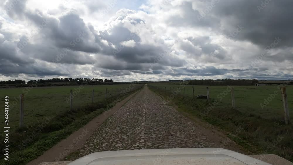 Video filmed from a Land Rover Defender on an overland trip through Portugal on a straight and flat cobbled road with stones, green grass on the sides Video filmed from a Land Rover Defender on an overland trip through Portugal on a straight and flat cobbled road with stones, green grass on the sides