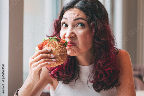 A girl sniffs a spoiled burger. Fast food diet and food poisoning concept photo