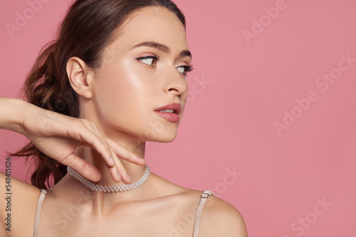 Young woman wearing elegant pearl necklace on pink background, space for text