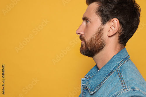 Profile portrait of bearded man on orange background. Space for text