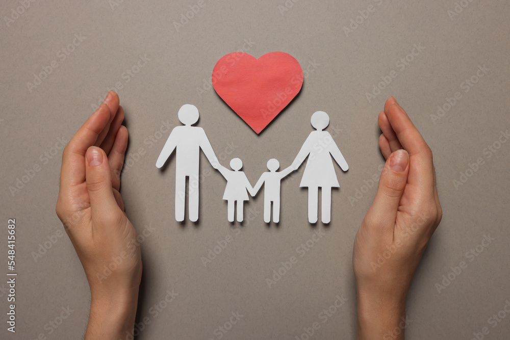 Woman protecting paper family figures and red heart on light grey background, top view. Insurance concept Woman protecting paper family figures and red heart on light grey background, top view. Insurance concept