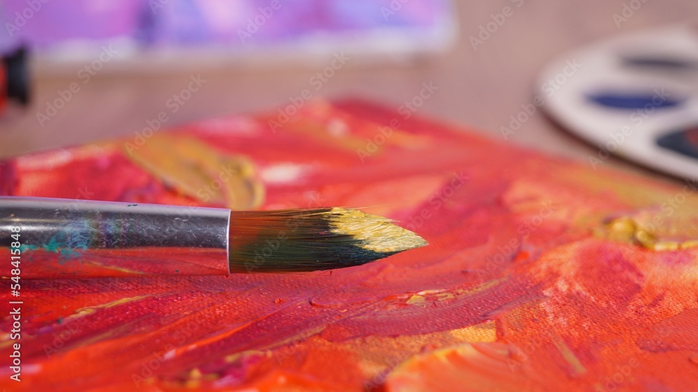 Fototapeta premium Artist's canvas with mixed paints and brush on table, closeup