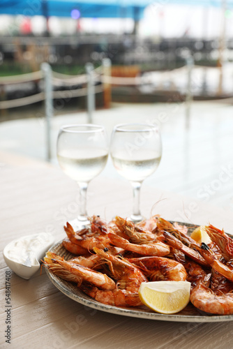 Plate of delicious cooked shrimps served with lemon and wine at table outdoors