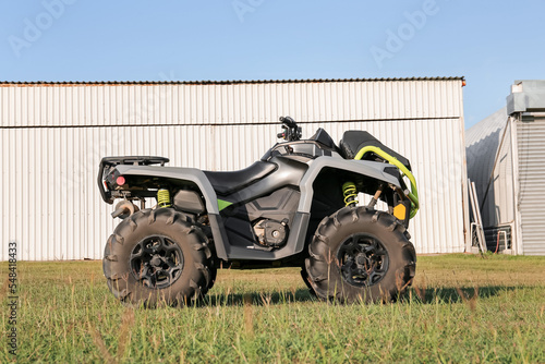 Modern quad bike in field near hangars on sunny day