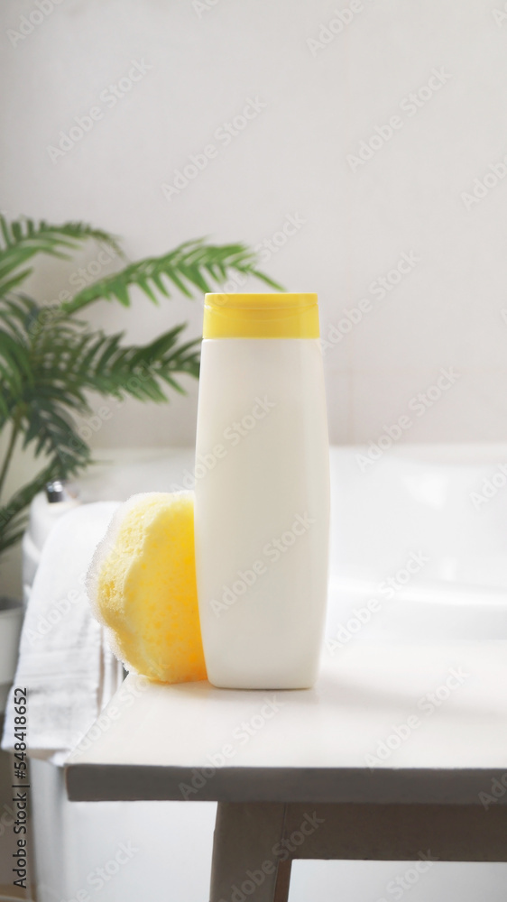 Bottle with foam bath and sponge on small table in bathroom Bottle with foam bath and sponge on small table in bathroom