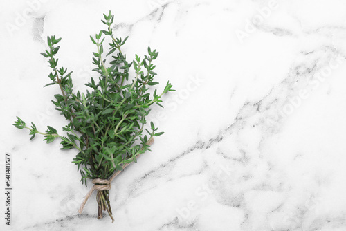 Bunch of aromatic fresh thyme on white marble table, top view. Space for text