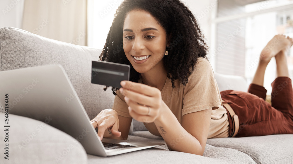 Credit card, laptop and online shopping with a black woman customer lying on a sofa in a living room of her home. Computer, ecommerce and retail with a female consumer spending money on the internet Credit card, laptop and online shopping with a black woman customer lying on a sofa in a living room of her home. Computer, ecommerce and retail with a female consumer spending money on the internet