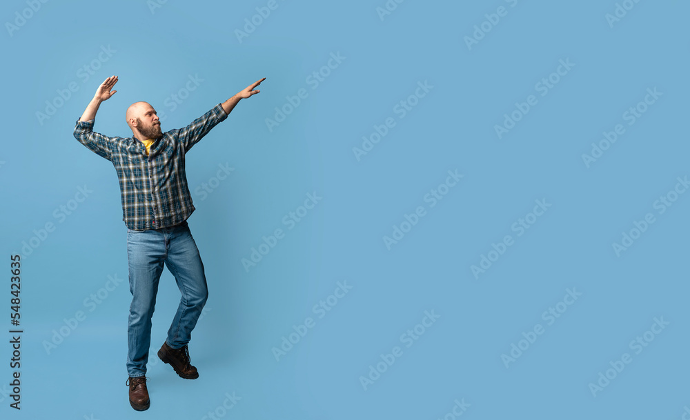 Bearded positive smile caucasian man showing to the right over blue background. Mock up, template, copy space. Confident, handsome. Casual blue clothing and jeans. Positive advertising concept