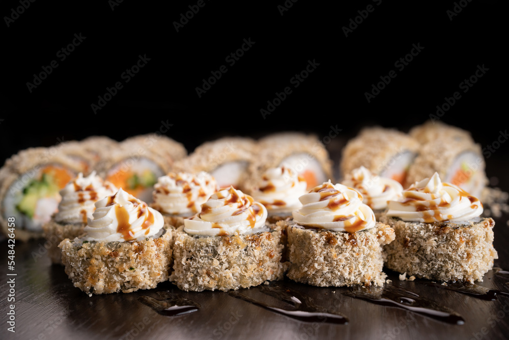 Set hot sushi rolls fried decorated cream cheese. Assortment of delicious tempura and baked sushi maki with salmon. Sushi volcano on black background Set hot sushi rolls fried decorated cream cheese. Assortment of delicious tempura and baked sushi maki with salmon. Sushi volcano on black background