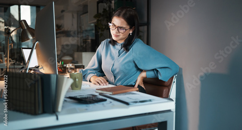 Business woman, computer or back pain in night office, digital marketing startup or advertising agency company. Tired, stress injury or worker on web design technology and sciatica crisis or burnout photo