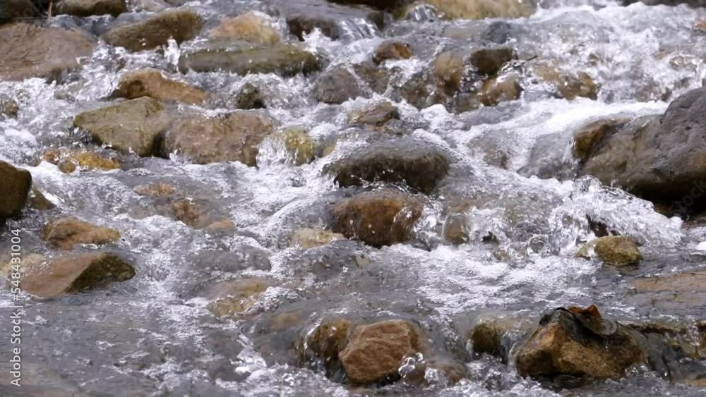 Clear stream running through stone boulders Abundant river flowing in slow motion. Wild mountain river water splashing in summer near the river bank environment. Clear stream running through stone boulders Abundant river flowing in slow motion. Wild mountain river water splashing in summer near the river bank environment.