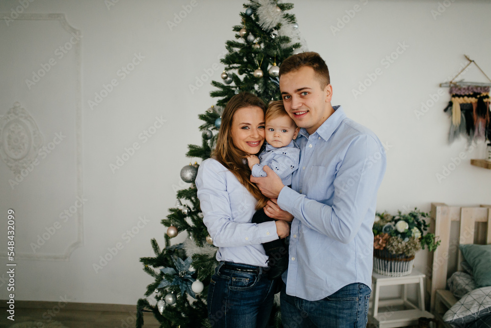 Happy smiling family at studio on background of the Christmas tree with gift Happy smiling family at studio on background of the Christmas tree with gift
