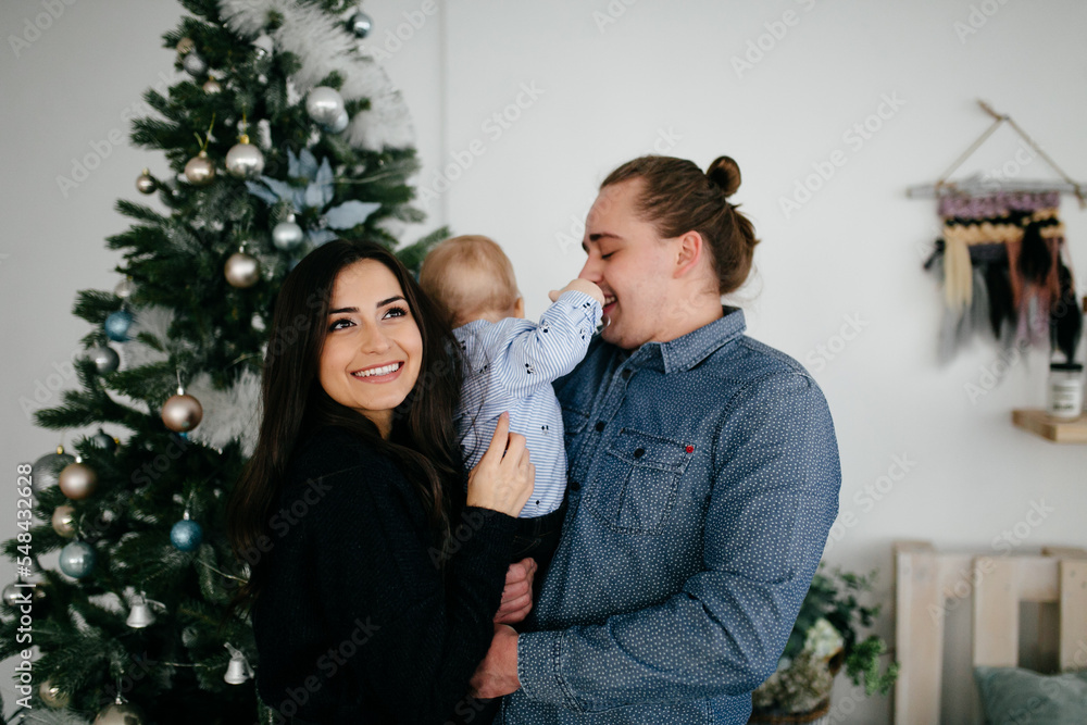 Happy smiling family at  studio on background of the Christmas tree with gift