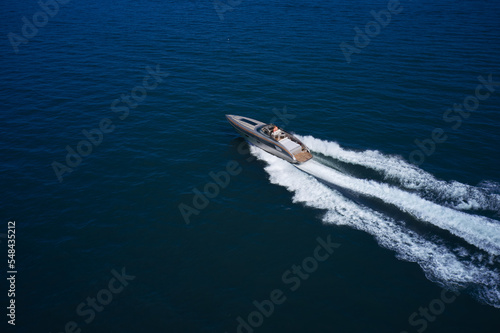 Super speedy big gray boat fast moving on dark water top view. Boat super luxury with people fast movement on the dark sea.