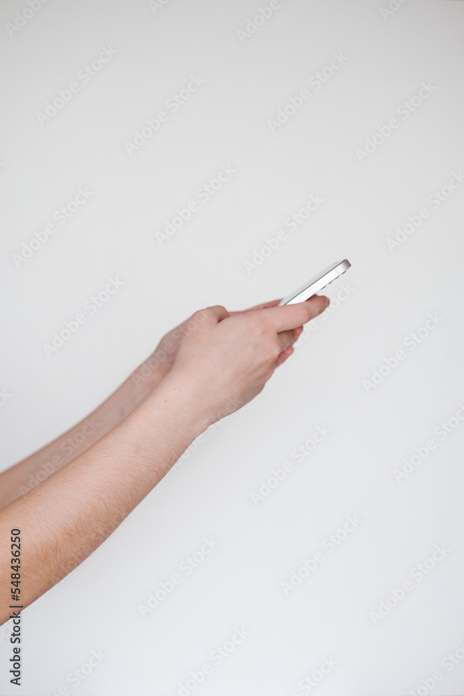 two hands of a freelancer on the side holding a white phone on a white background two hands of a freelancer on the side holding a white phone on a white background