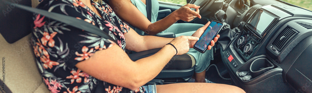 Unrecognizable women looking at the gps on the mobile during a trip in a camper van Unrecognizable women looking at the gps on the mobile during a trip in a camper van