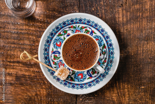 Turkish coffee in classic coffee cup with water and Turkish delight on wooden table © yalcinsonat