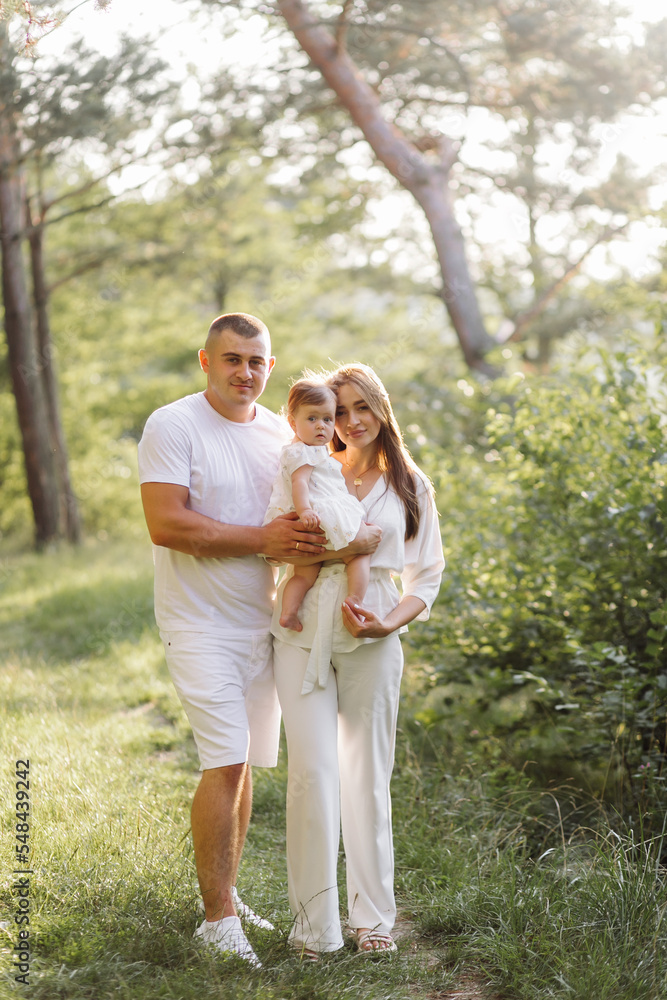Young family with cute little daughter walking in forest on the sunset Young family with cute little daughter walking in forest on the sunset