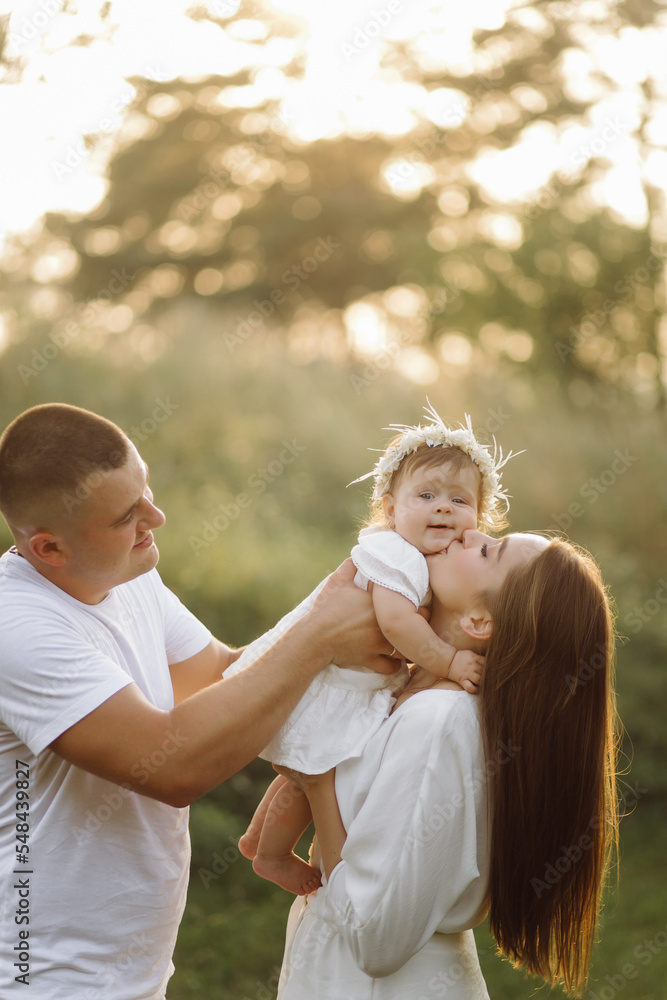 Fototapeta premium Young family with cute little daughter walking in forest on the sunset
