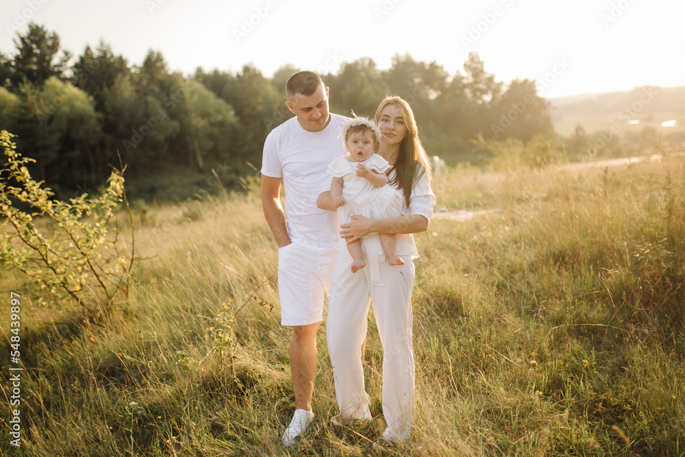 Young family with cute little daughter walking in forest on the sunset Young family with cute little daughter walking in forest on the sunset