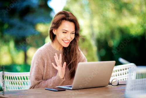 Attractive brunette haired woman sitting outdoor at home and using a laptop