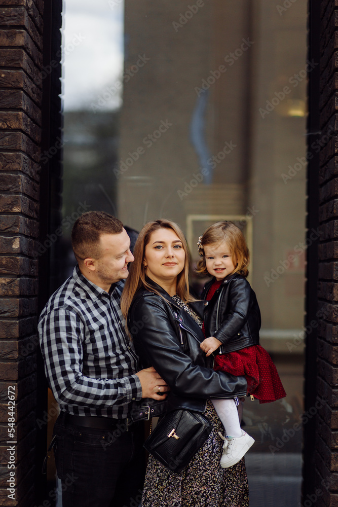 Fototapeta premium Parents and daughhter walking around the city. Spend time together. They are happy