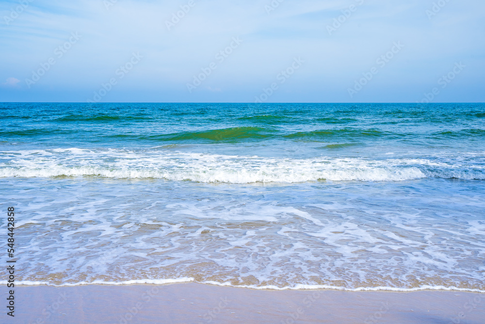 Light blue sea waves on a clean sandy beach..