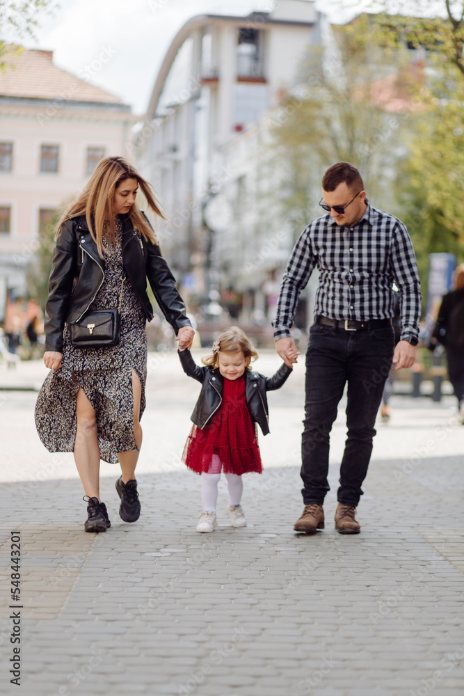 Parents and daughhter walking around the city. Spend time together. They are happy