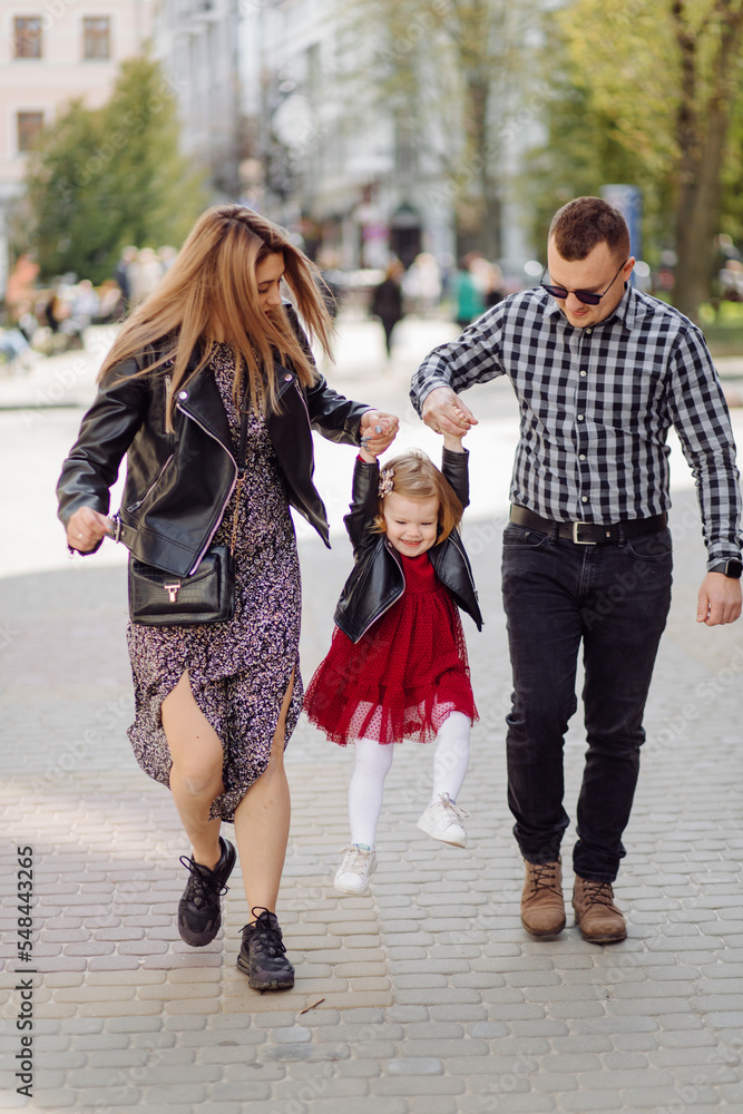 Parents and daughhter walking around the city. Spend time together. They are happy