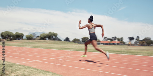 Runner, fitness and fast black woman in stadium for professional race, competition or training. Sprint, performance and champion running athlete on sport ground with blur speed movement or motion. © L Ismail/peopleimages.com
