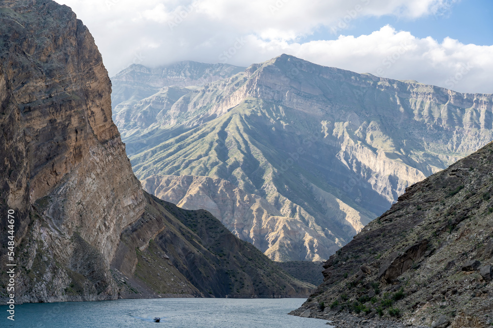 Motor boat on scenic turquoise river among rocks and mountains