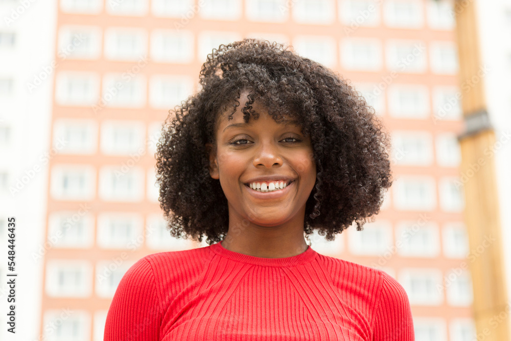 portrait of smiling african american young woman with building in background portrait of smiling african american young woman with building in background