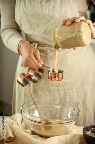 Vertical closeup of female hands pouring baking cookie on the glass bowl other ingredients around