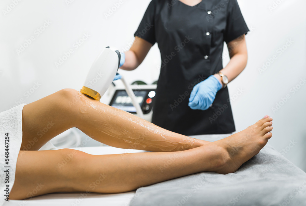 closeup view of a cosmetologist removing hair from a client's legs, laser depilation apparatus, modern technology beauty treatment. High quality photo