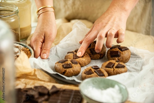 Closeup of female hands putting cookies on the black baking sheet pouring on ingredients around