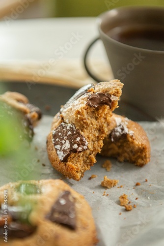 Vertical closeup of coffee cup and freshly baked cookies blurred background